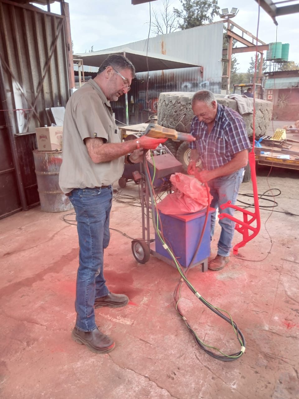 Powder coating a steel item red in the workshop