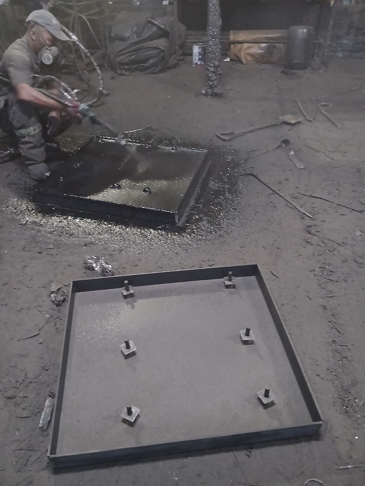 Spraying black rubber lining onto steel in the yard